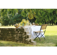 Gedekte tuintafel met muur en klapstoel op gazon