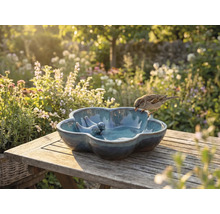 Keramische vogeldrinkbak met vogeldecoratie op houten tafel in de tuin