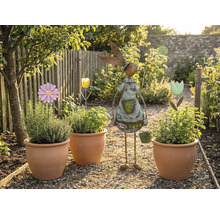 Tuinscene met beplante terracotta potten, bloemstekers en een tuindecoratie in de vorm van een konijn