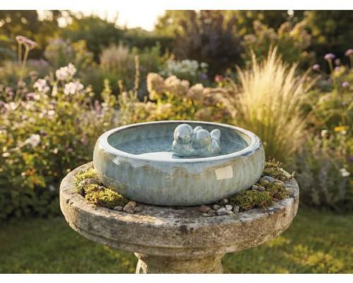 Keramische vogeldrinkbak met vogelpaar in de tuin