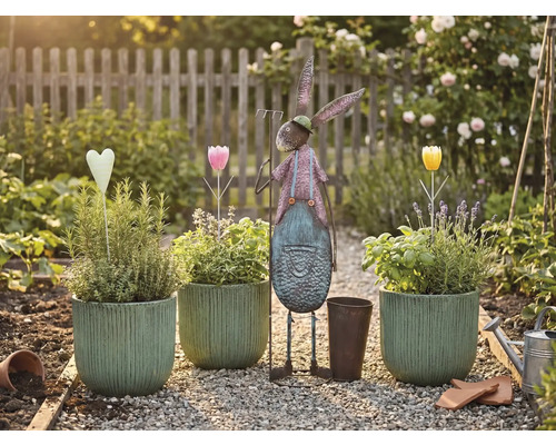 Tuinscene met beplante potten, metalen haas en decoraties op een grindpad