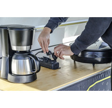 Iemand steekt een koffiezetapparaat in een stekkerdoos.