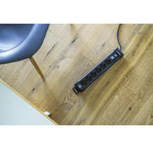 Meervoudig stopcontact op een houten vloer naast een stoel.