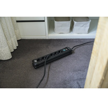 Verlengsnoer met zes stopcontacten en schakelaar op een vloerkleed