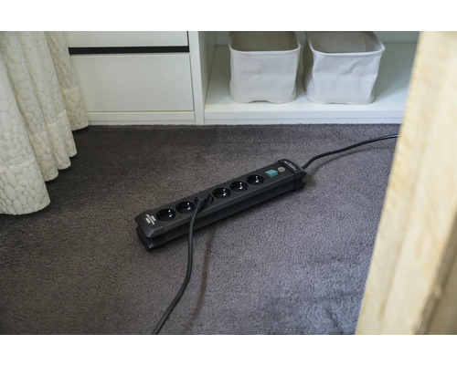 Verlengsnoer met zes stopcontacten en schakelaar op een vloerkleed