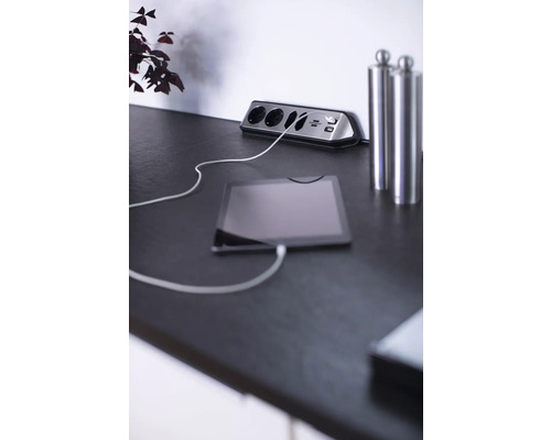 Stekkerdoos met USB-poorten en aangesloten tablet op een tafel