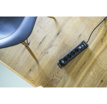 Verlengdoos met overspanningsbeveiliging en schakelaar op een houten vloer.