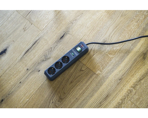 Verlengsnoer met drie stopcontacten en overspanningsbeveiliging op houten vloer