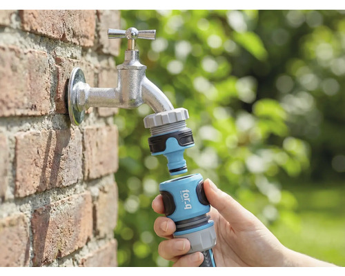 Tuinscène met waterkraan, hierop aangesloten een for_q tuinslangkoppeling in de hand