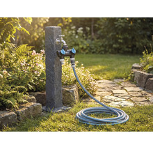 Tuinscène met waterkraan, verdeelstuk en tuinslang op een gazon