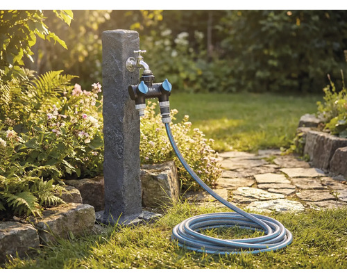 Tuinscène met waterkraan, verdeelstuk en tuinslang op een gazon