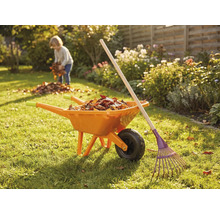 Tuinscene met kruiwagen, hark en kind dat bladeren verzamelt