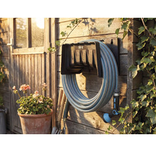 Tuinscene met slanghaspel, gemonteerd aan een houten wand met tuinslang