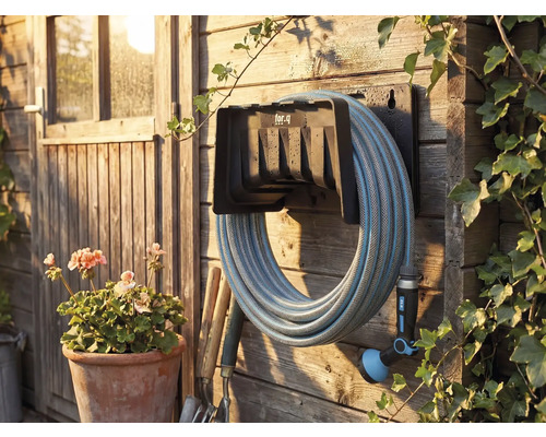 Tuinscene met slanghaspel, gemonteerd aan een houten wand met tuinslang