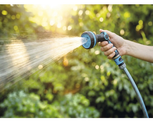 Hand houdt tuinslang met sproeikop vast tijdens het besproeien