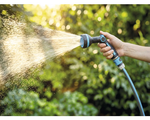 Hand houdt tuinslang met sproeikop vast