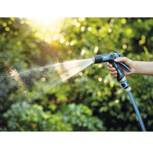 Een persoon houdt een tuinspuit vast en geeft planten water.