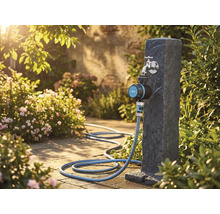 Tuinscene met waterkraan, irrigatietimer en tuinslang