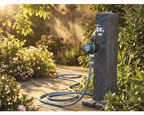 Tuinscene met waterkraan, irrigatietimer en tuinslang