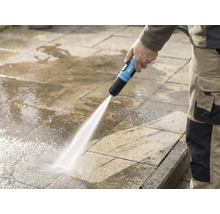 Een persoon reinigt een stenen terras met een for_q-tuinslang