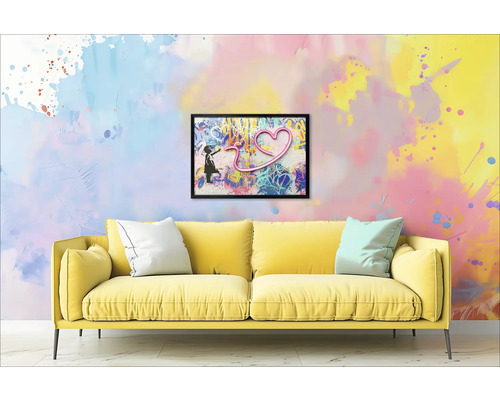 Gele bank met kussens voor een muur met een ingelijste afbeelding van een meisje en een hart