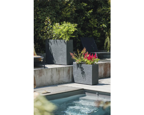 Twee rechthoekige plantenbakken van steen naast een zwembad in de tuin.
