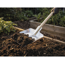 Spade met houten handvat en aarde in de tuinbedding