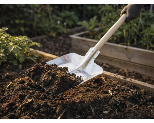 Spade met houten handvat en aarde in de tuinbedding
