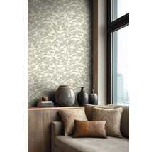 Lichte, modern ingerichte woonkamer met behang met boompatroon, een houten dressoir met vazen en een bank met kussens.