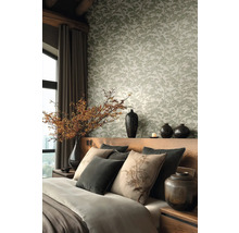 Vliesbehang met dennenboompatroon in een slaapkamer met houten hoofdbord, decoratieve kussens en keramieken vazen met takken.