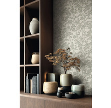 Behang met fijn boompatroon achter een donkere houten kast en diverse keramieken vazen.