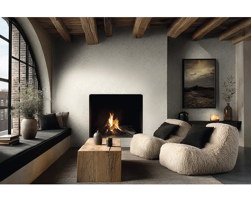 Moderne woonkamer met haard, getextureerde muren en houten plafondbalken. Fauteuils, een houten tafel en een gezellige vensterbank.