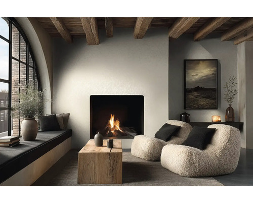 Gezellige woonkamer met brandende open haard, twee teddy fauteuils, salontafel van massief hout en houten plafondbalken in moderne landelijke stijl.