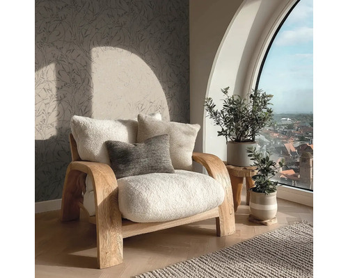 Lichte fauteuil met kussens naast kamerplanten en een raam