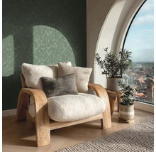 Lichte kamer met fauteuil, kussens, planten en uitzicht uit het raam