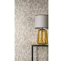 Vliesbehang met verticaal patroon van onregelmatige rechthoeken in een moderne kamer met een tafellamp op een bijzettafel.