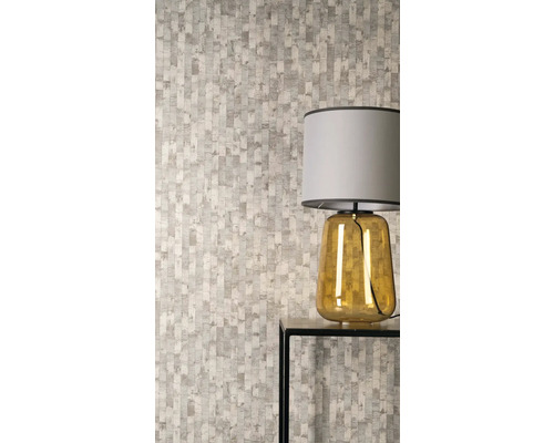 Vliesbehang met verticaal patroon van onregelmatige rechthoeken in een moderne kamer met een tafellamp op een bijzettafel.