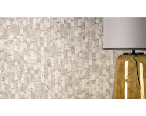 Vliesbehang met gestructureerd verticaal strepenpatroon en metallic accenten naast een tafellamp.