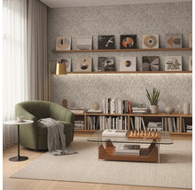 Modern ingerichte kamer met een groene fauteuil, glazen salontafel en houten planken tegen grijs gestructureerd behang.