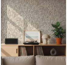 Wand met geometrisch patroonbehang in beige en grijs achter een houten dressoir met platenspeler en plant in een lichte woonkamer.