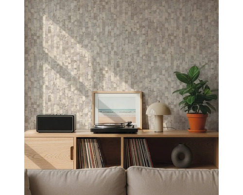 Wand met geometrisch patroonbehang in beige en grijs achter een houten dressoir met platenspeler en plant in een lichte woonkamer.