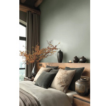 Moderne slaapkamer met houten hoofdbord, sierkussens en een grote vaas met bessentakken naast lange gordijnen.