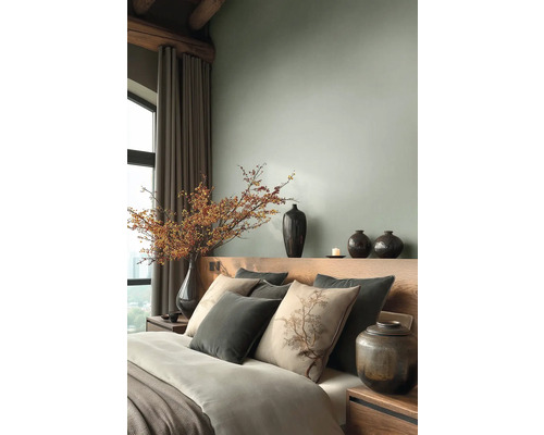 Moderne slaapkamer met houten hoofdbord, sierkussens en een grote vaas met bessentakken naast lange gordijnen.