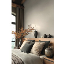 Slaapkamer met bed, kussens, vazen en decoratieve elementen voor een rustige sfeer