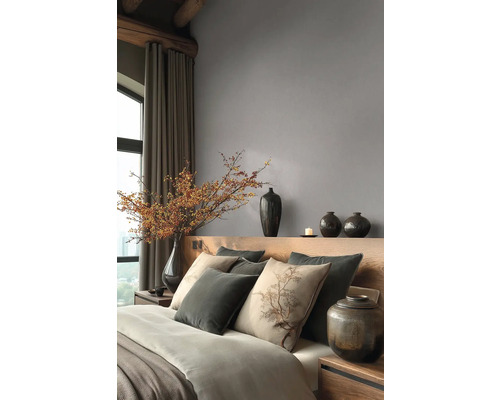 Moderne slaapkamer met grijs vliesbehang, houten hoofdbord, kussens met boommotief en decoratieve donkere vazen.