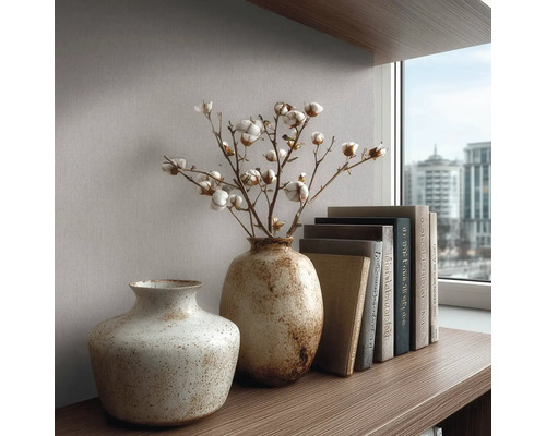 Getextureerde keramieken vazen met katoentakken en boeken op een houten plank voor behang bij een raam.