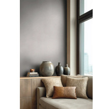 Moderne woonkamer met grijs-taupe behang, een bank met sierkussens en vazen op een dressoir bij een raam.