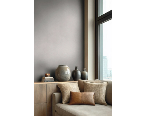 Moderne woonkamer met grijs-taupe behang, een bank met sierkussens en vazen op een dressoir bij een raam.