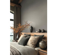 Moderne slaapkamer met houten hoofdbord, grijze muren, sierkussens, keramische vazen en een grote tak met bessen in een vaas.