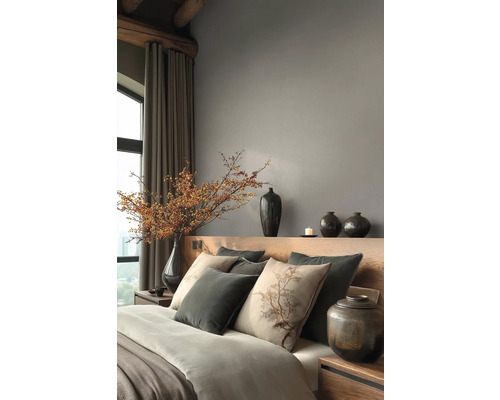 Moderne slaapkamer met houten hoofdbord, grijze muren, sierkussens, keramische vazen en een grote tak met bessen in een vaas.